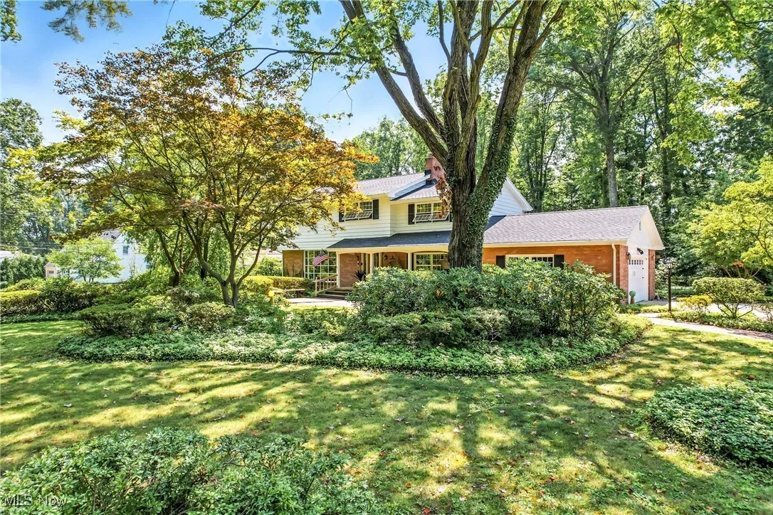 View of front facade featuring a porch, brick siding, a front lawn, an attached garage, and a shingled roof