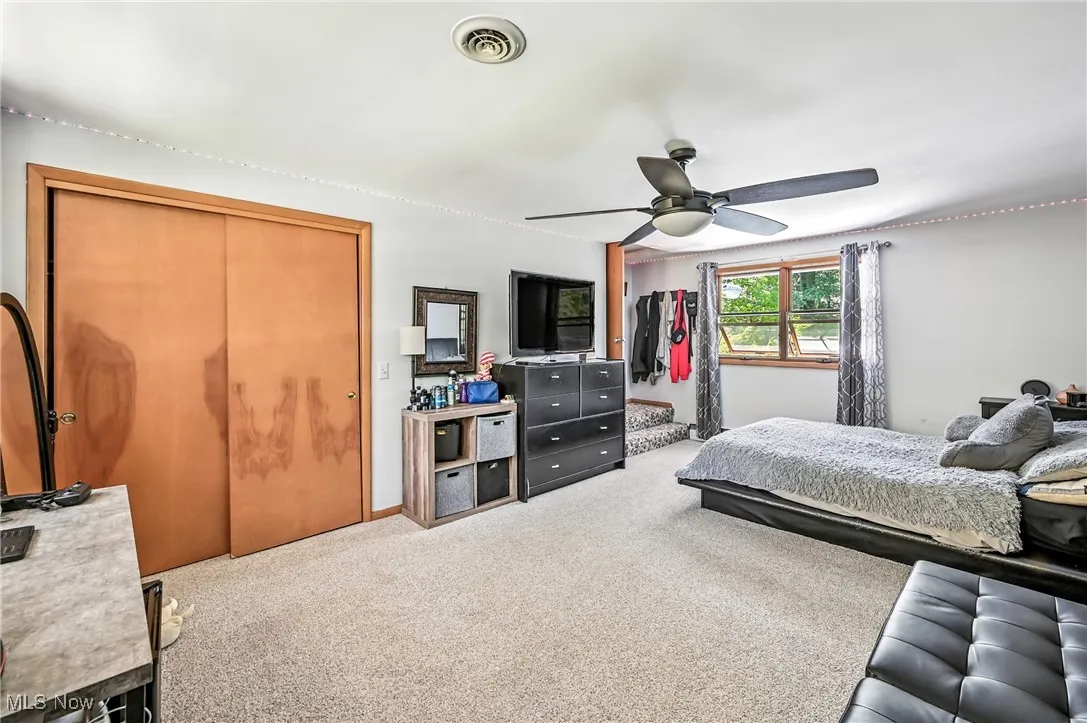 Carpeted bedroom with ceiling fan and baseboards