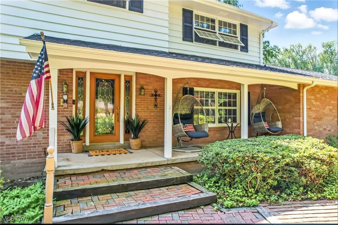 Entrance to property with covered porch and brick siding
