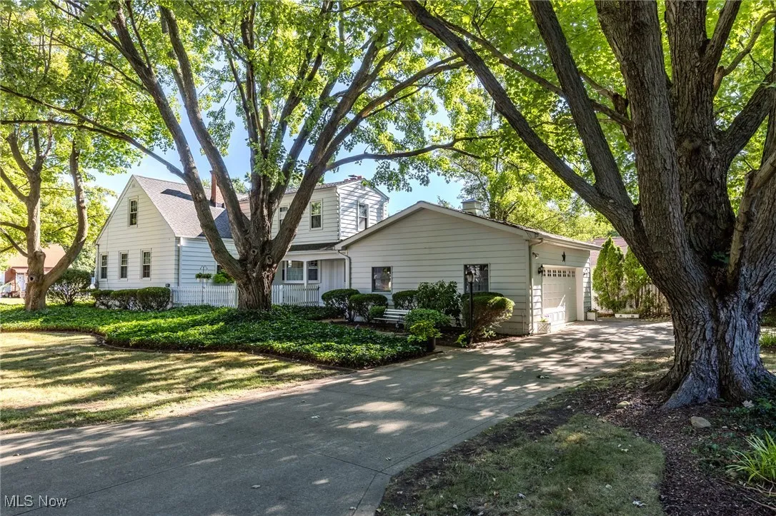 View of front of house featuring concrete driveway, a garage, and a chimney