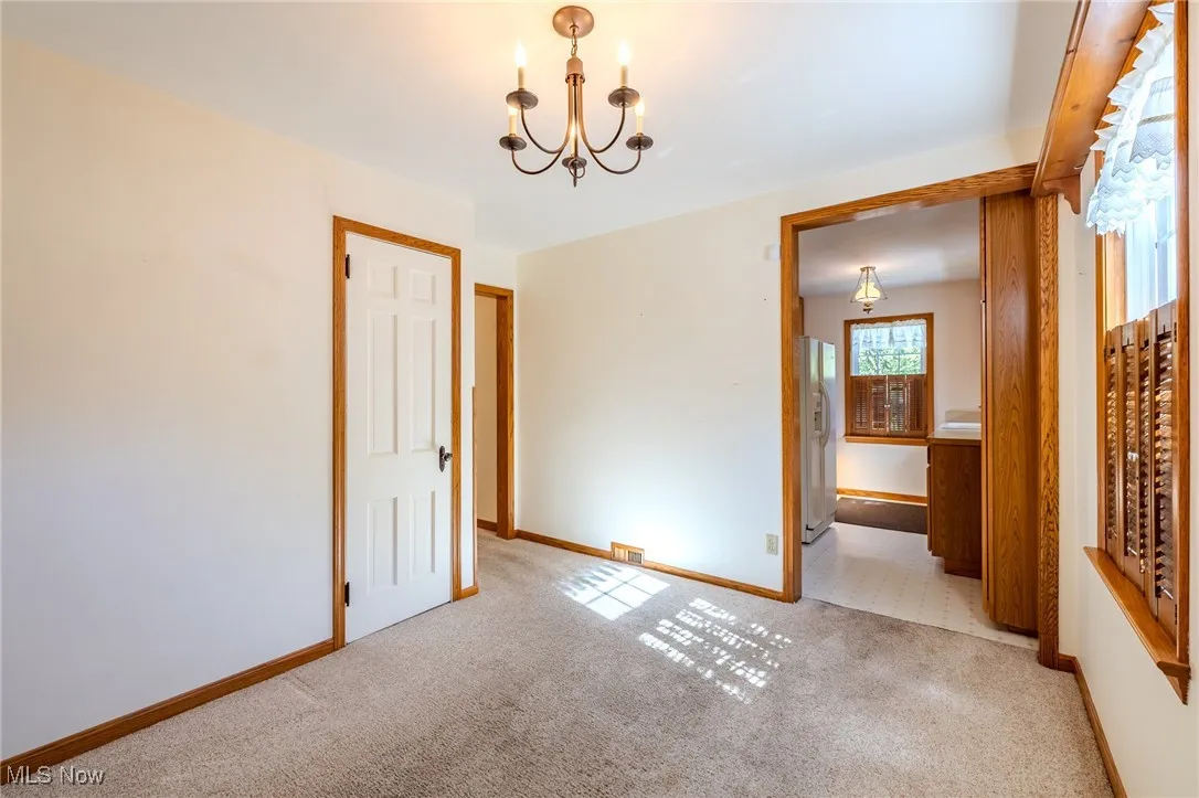 Unfurnished dining area featuring a chandelier and carpet floors