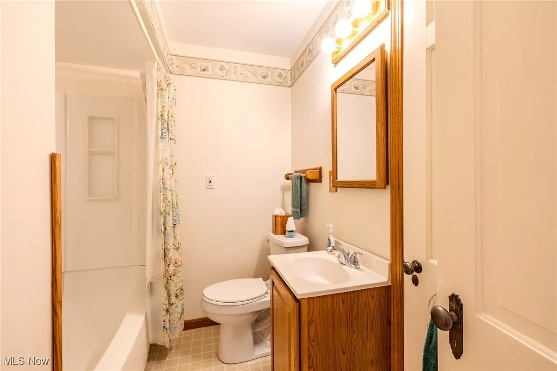Full bath featuring vanity, light tile patterned floors, and shower / tub combo with curtain