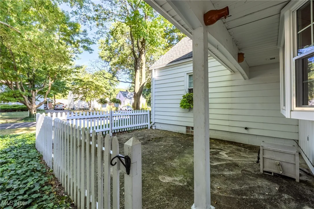 View of side of home with a shingled roof and a gate