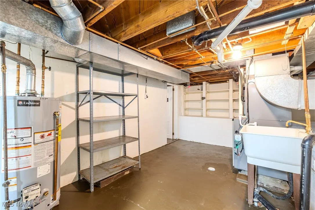 Unfinished below grade area with water heater and a sink