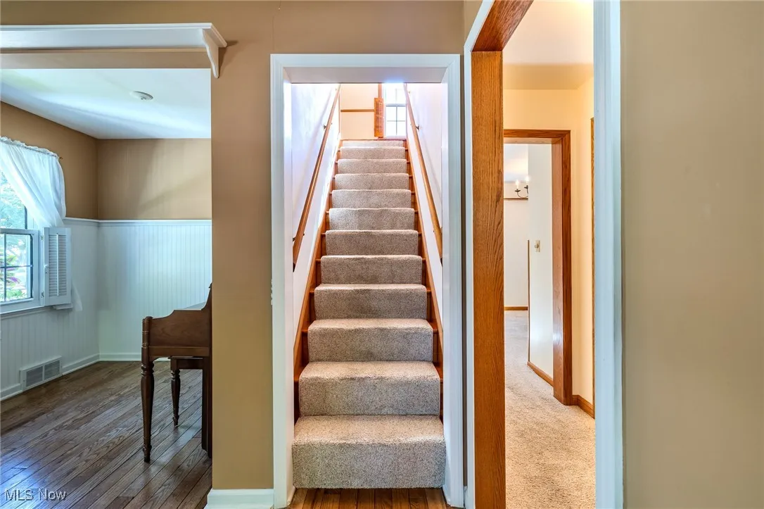 Stairway with wood-type flooring and a wainscoted wall