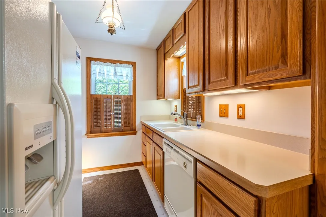 Kitchen featuring white appliances, brown cabinets, and light countertops