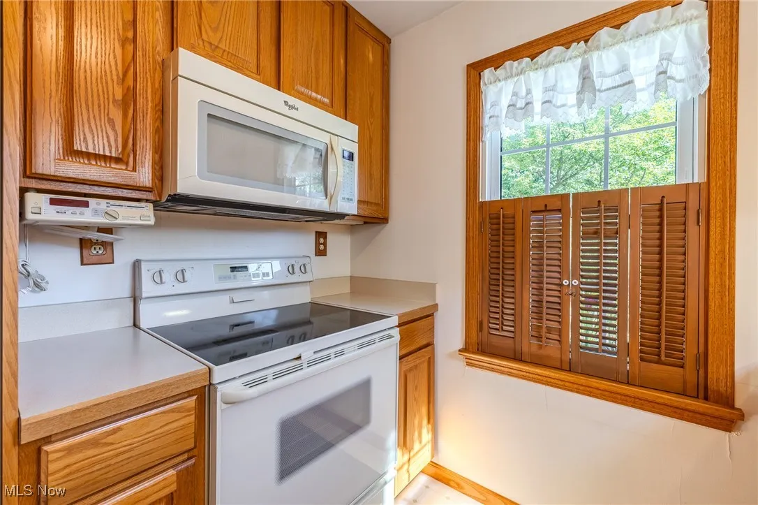 Kitchen with white appliances, light countertops, and brown cabinets