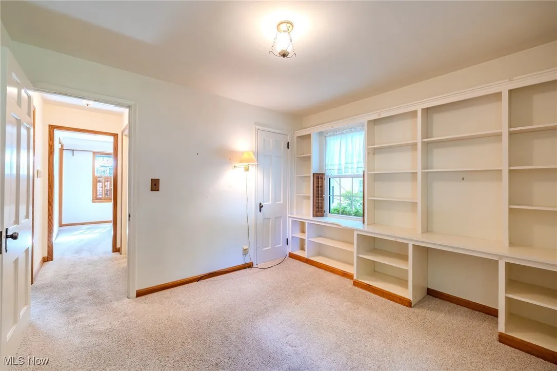 First floor bedroom featuring light colored carpet and baseboards