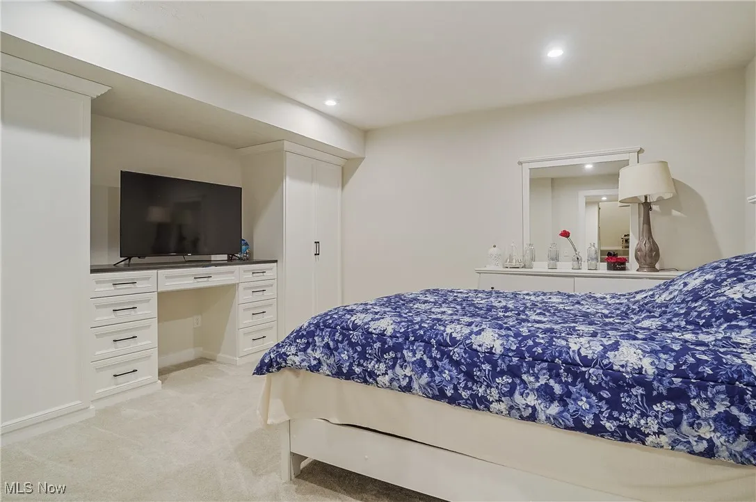 Bedroom with light colored carpet, recessed lighting, and built in study area