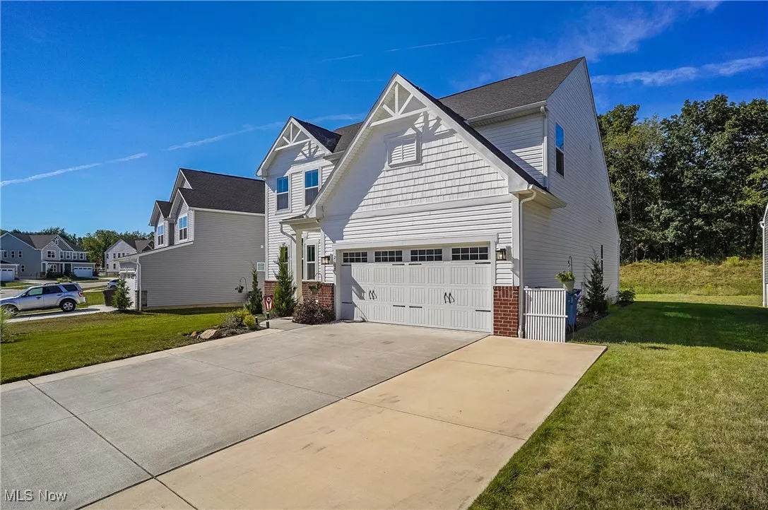 View of front of property featuring driveway, a front yard, brick siding, and a residential view