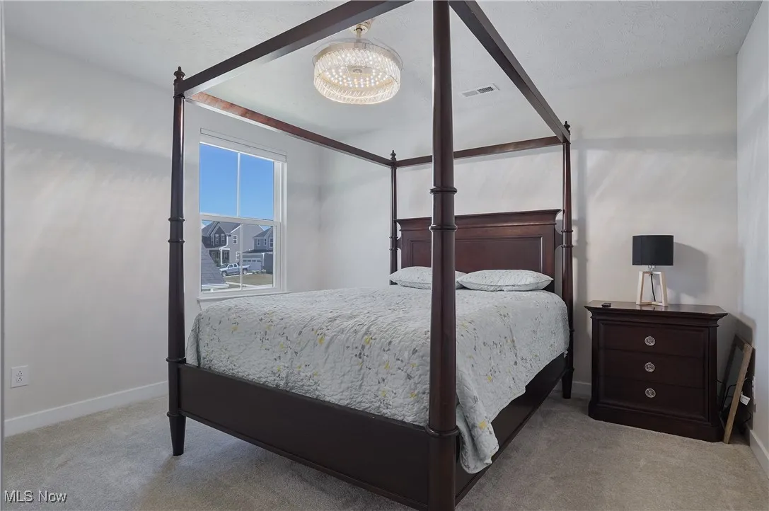 Bedroom featuring light carpet, a textured ceiling, and a chandelier