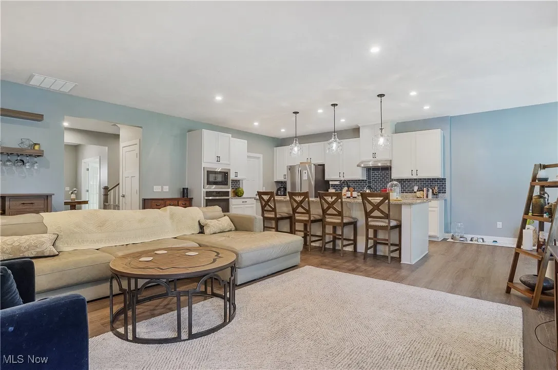 Living area with light wood-type flooring and recessed lighting