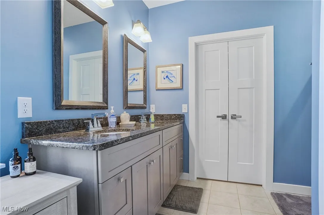 Full bathroom with double vanity and light tile patterned floors