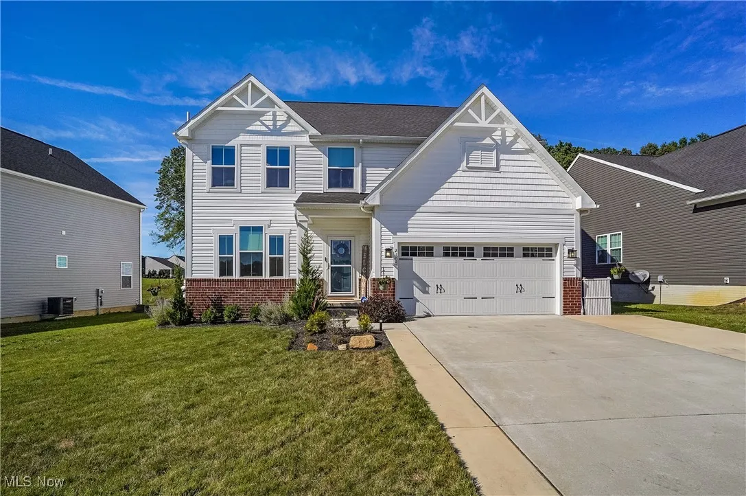 Craftsman inspired home featuring brick siding, driveway, a front yard, and an attached garage
