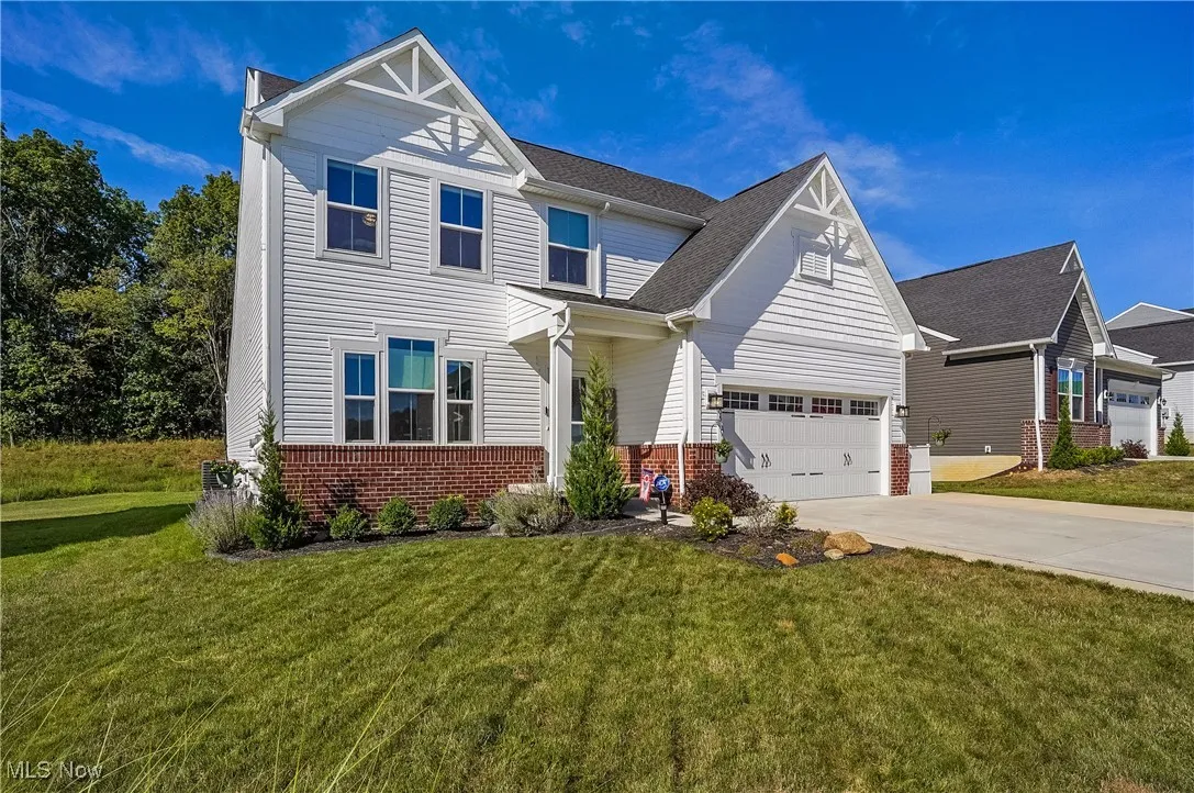View of front of property featuring brick siding, driveway, a front yard, and an attached garage