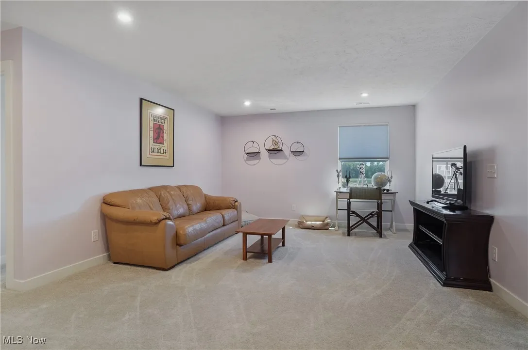Living area with light colored carpet and recessed lighting