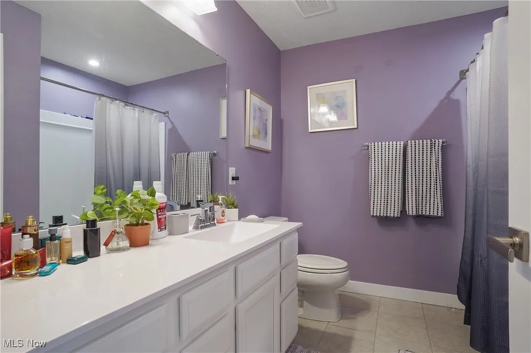 Bathroom with light tile patterned flooring, vanity, and curtained shower