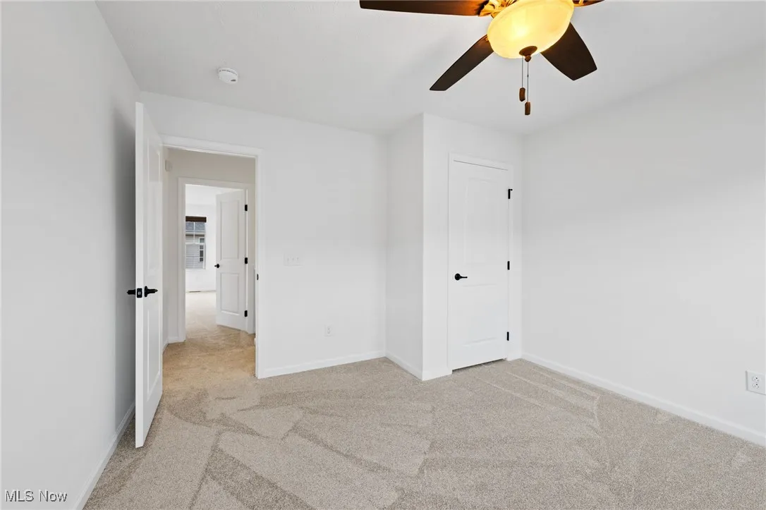 Unfurnished bedroom with light carpet and ceiling fan