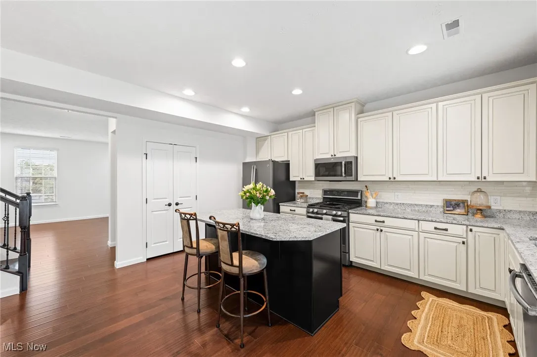 Kitchen featuring tasteful backsplash, stainless steel appliances, a center island, and a light stone counters