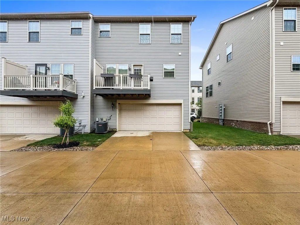 Back of property with concrete driveway, a deck, and an attached garage