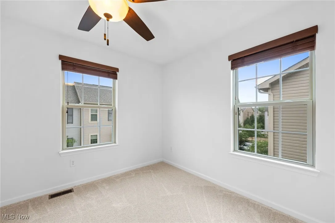 Bedroom featuring light colored carpet, healthy amount of natural light, and a ceiling fan