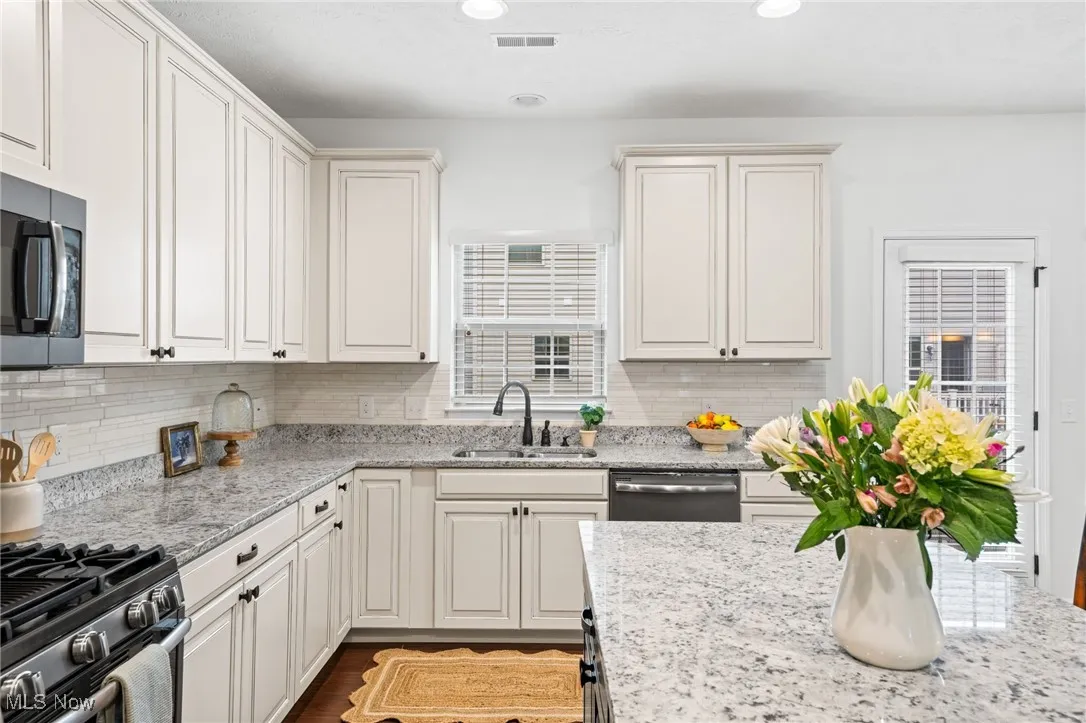 Kitchen featuring light stone countertops, tasteful backsplash, healthy amount of natural light, appliances with stainless steel finishes, and recessed lighting