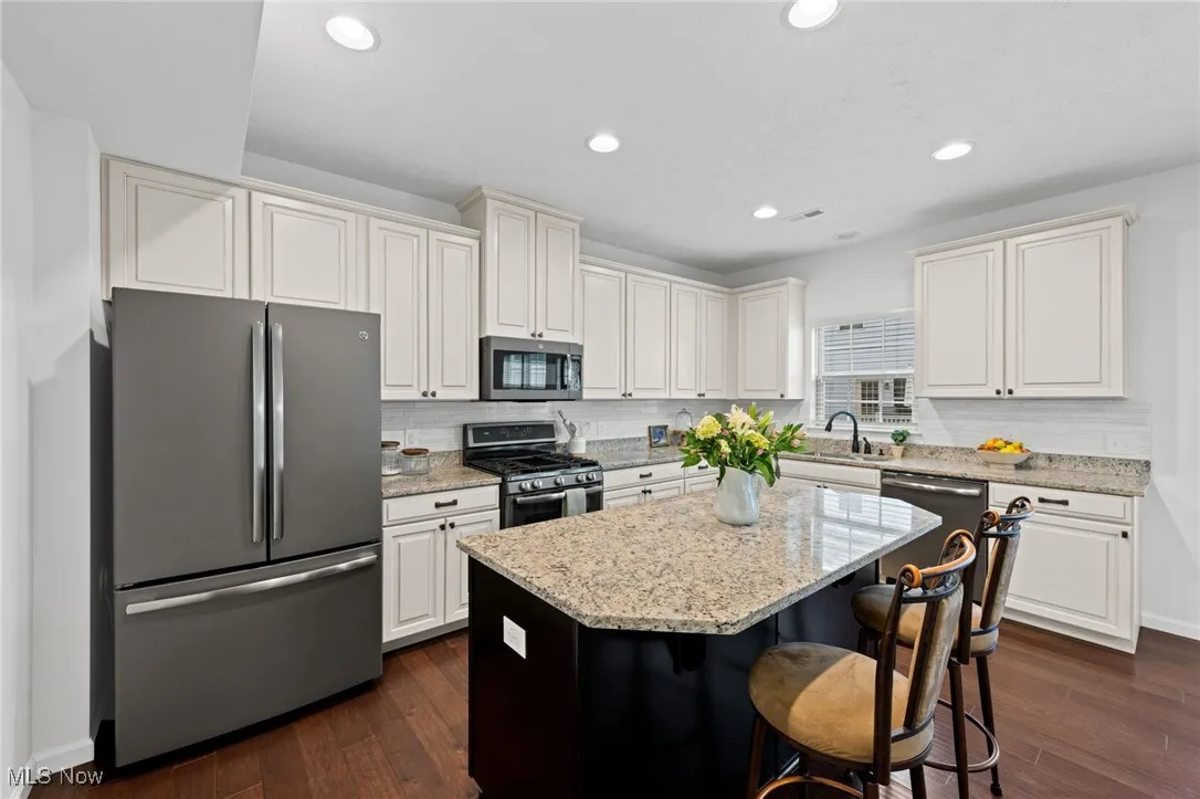 Kitchen with appliances with stainless steel finishes, light stone countertops, dark wood-style flooring, and recessed lighting