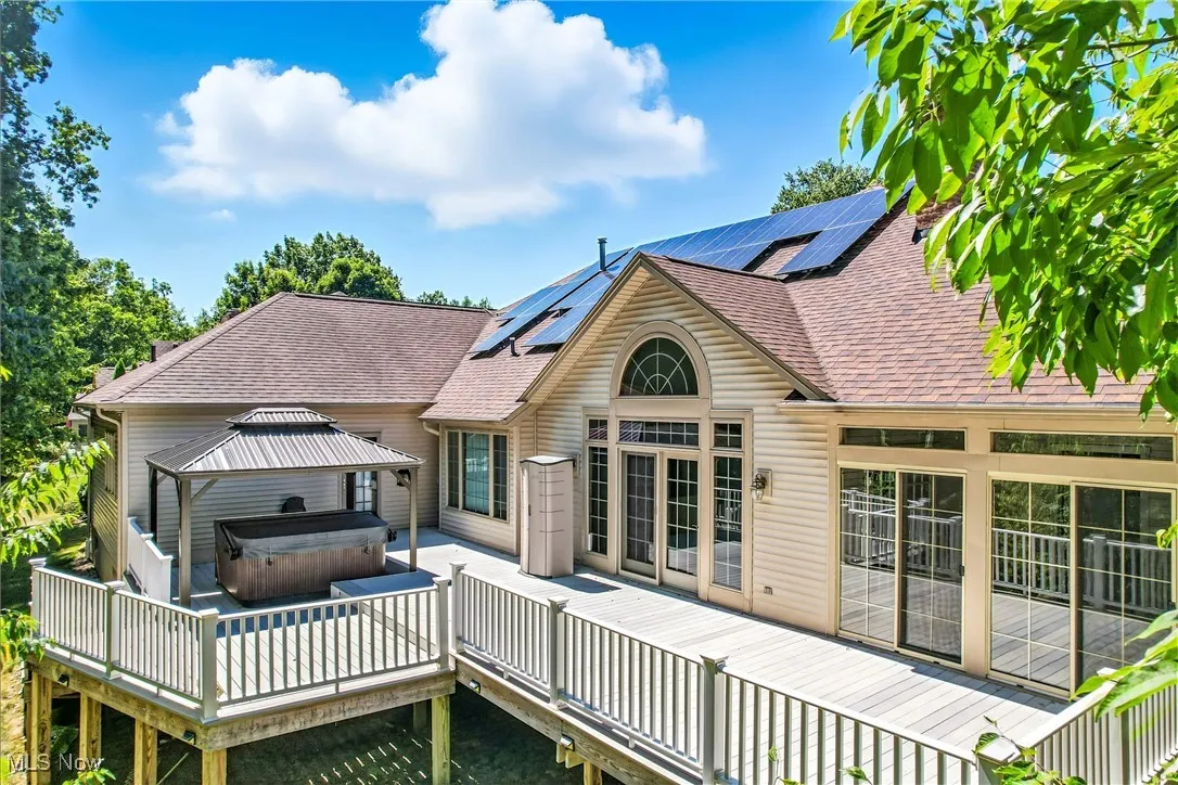 Back of property featuring a hot tub, roof 2018, a deck, solar panels, and a gazebo