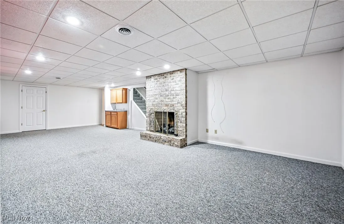 Finished below grade area featuring a fireplace, a drop ceiling, carpet floors, and recessed lighting, opportunity for in law suite
