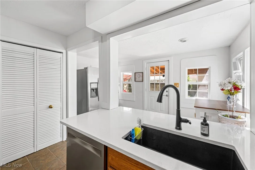 Kitchen with stainless steel appliances, dark tile patterned floors, and light stone countertops