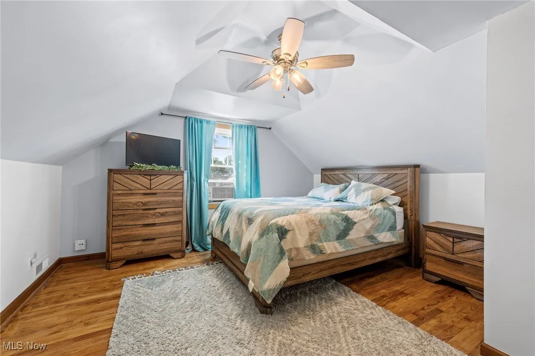 Bedroom with vaulted ceiling, wood finished floors, and ceiling fan