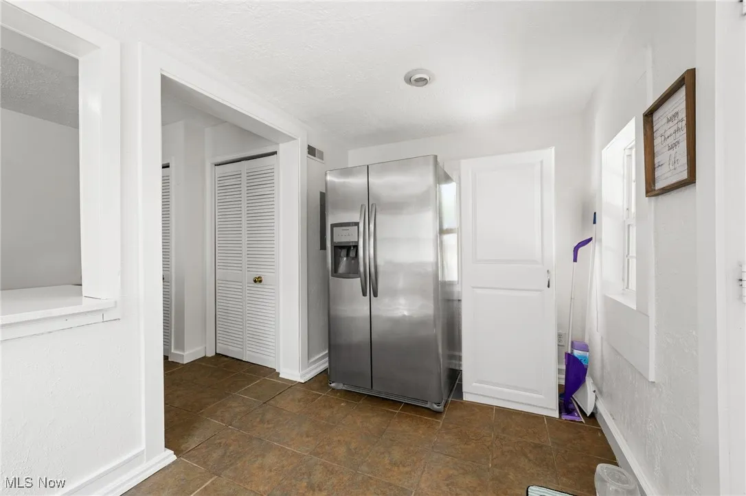 Hall with a textured ceiling and dark tile patterned floors