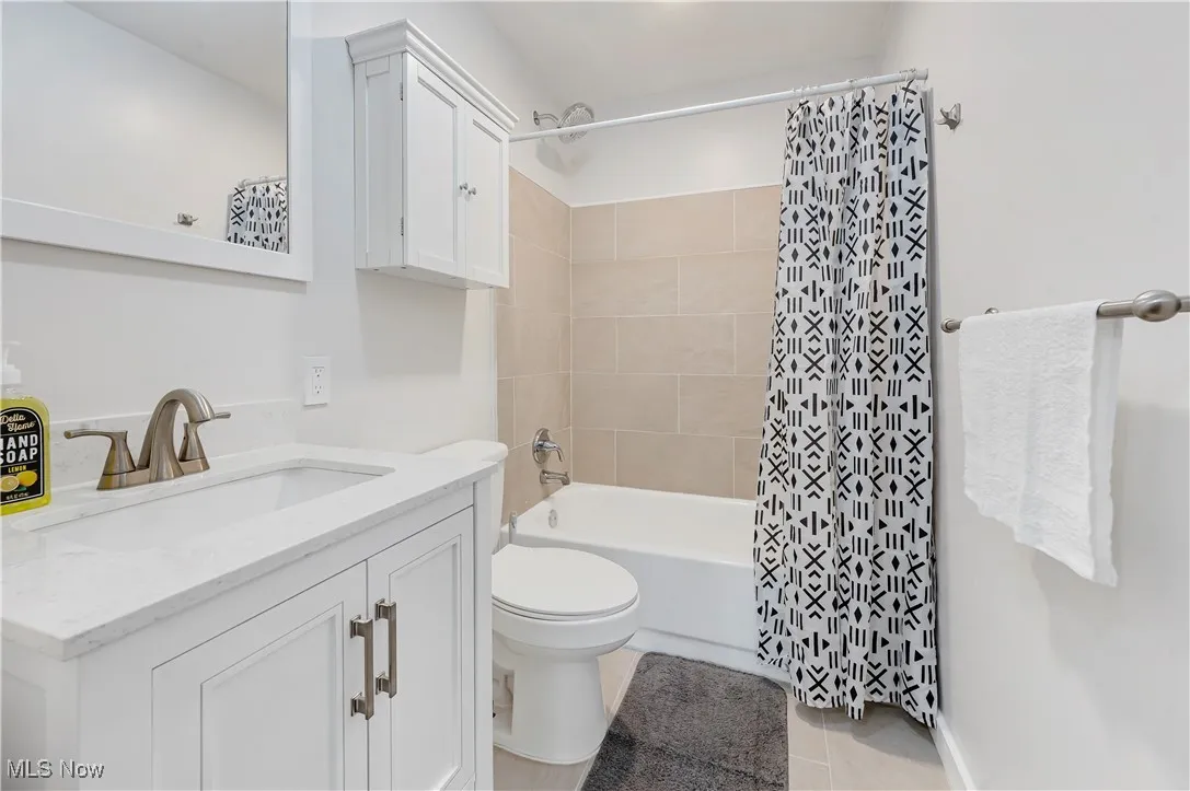 Bathroom featuring vanity, shower / tub combo, and light tile patterned floors