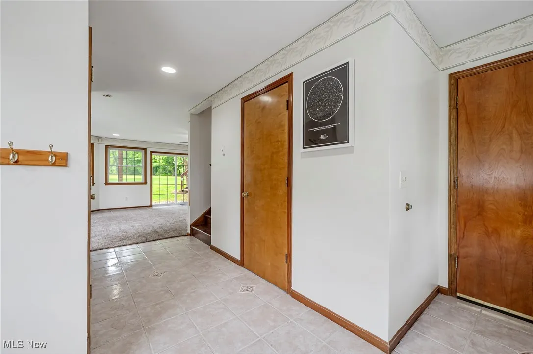 Corridor with light tile patterned floors, recessed lighting, and stairway