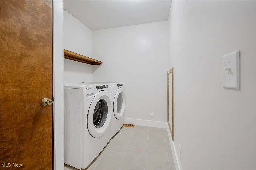 Laundry area with light tile patterned floors and washer and clothes dryer