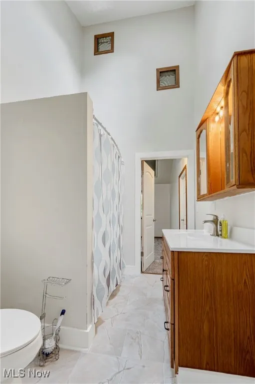 Full bathroom featuring vanity, a towering ceiling, and a shower stall