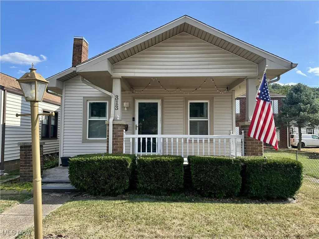 Bungalow with a porch, a chimney, and a front lawn
