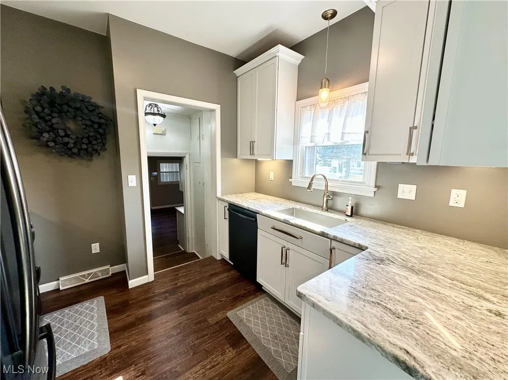 Kitchen with white cabinets, wood-type flooring, and dishwasher