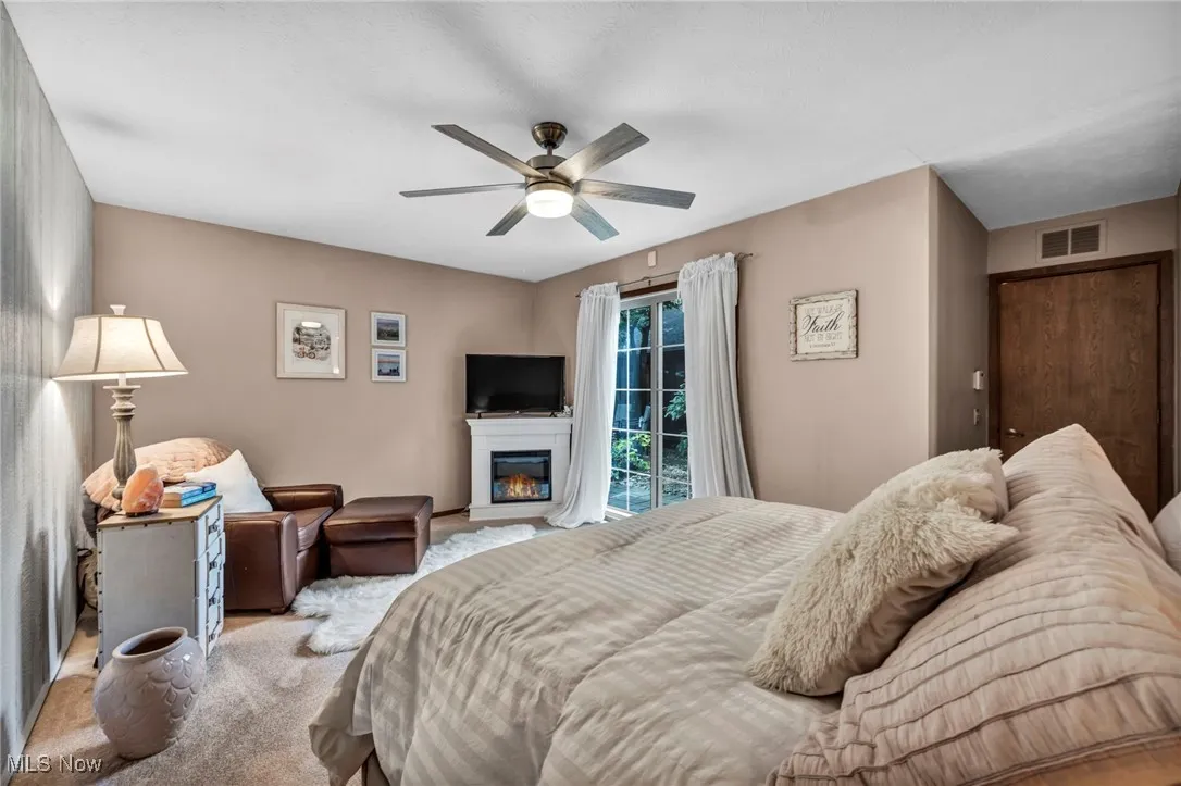 Bedroom with a glass covered fireplace and ceiling fan