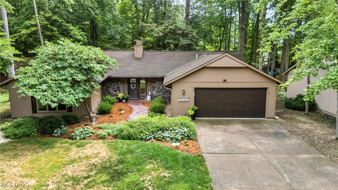 View of front of home featuring a garage, driveway, a chimney, a shingled roof, and a front yard