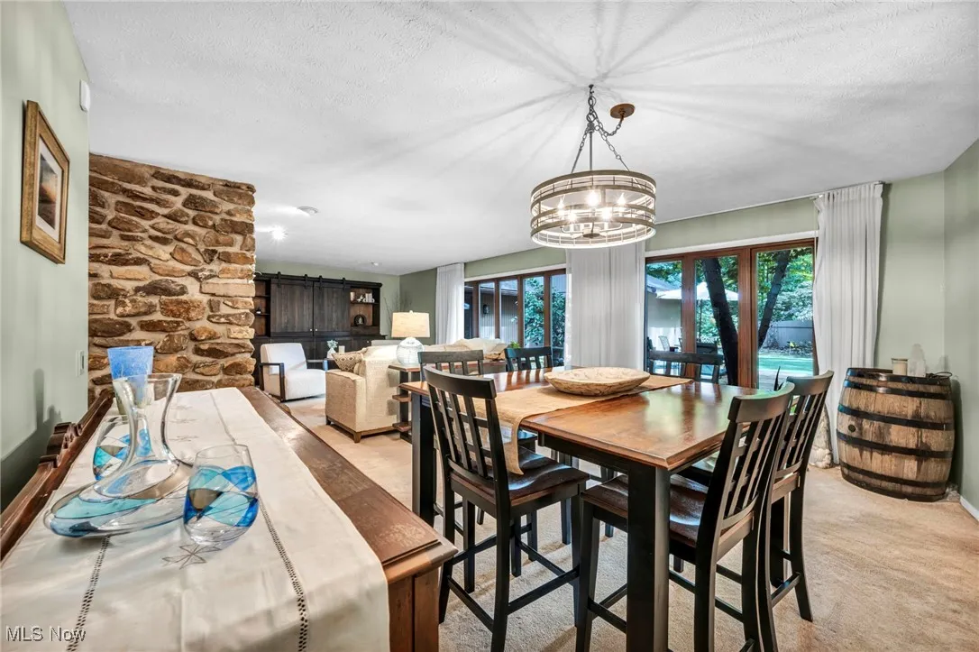 Dining area featuring a textured ceiling, light colored carpet, and a chandelier