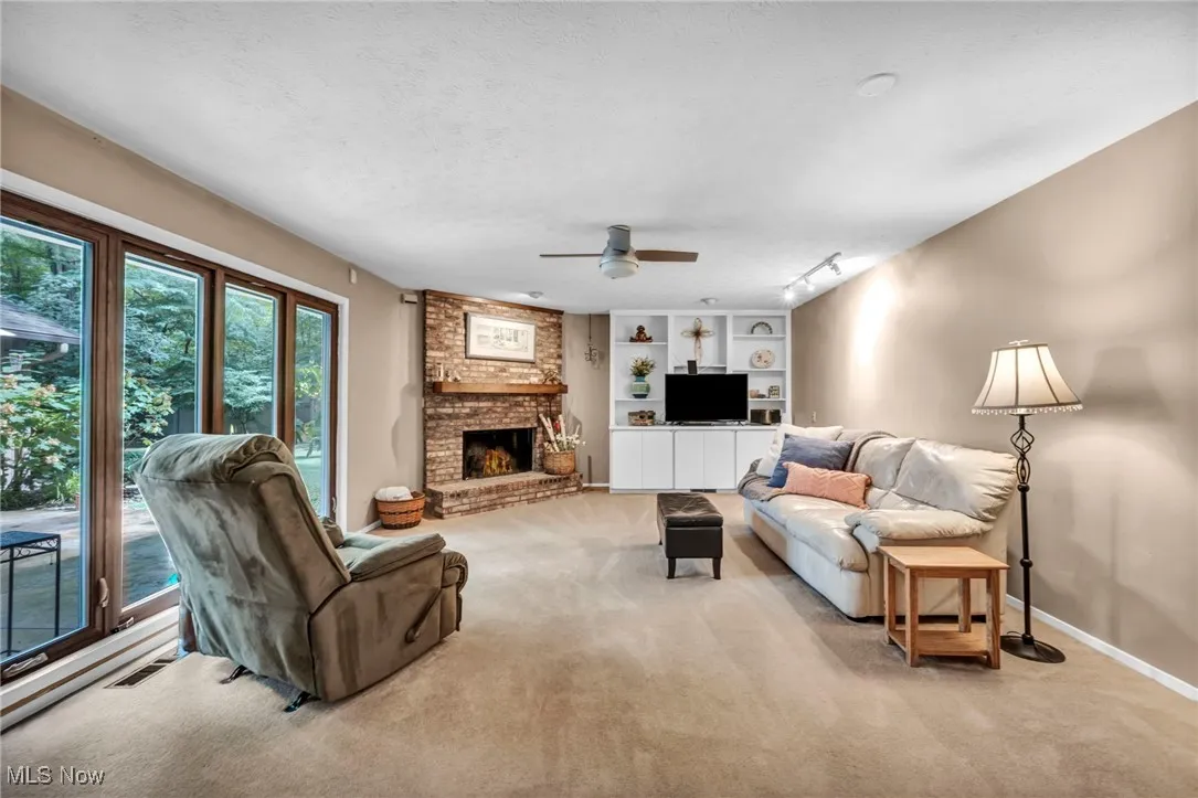 Carpeted living area featuring a textured ceiling, a fireplace, a ceiling fan, and rail lighting
