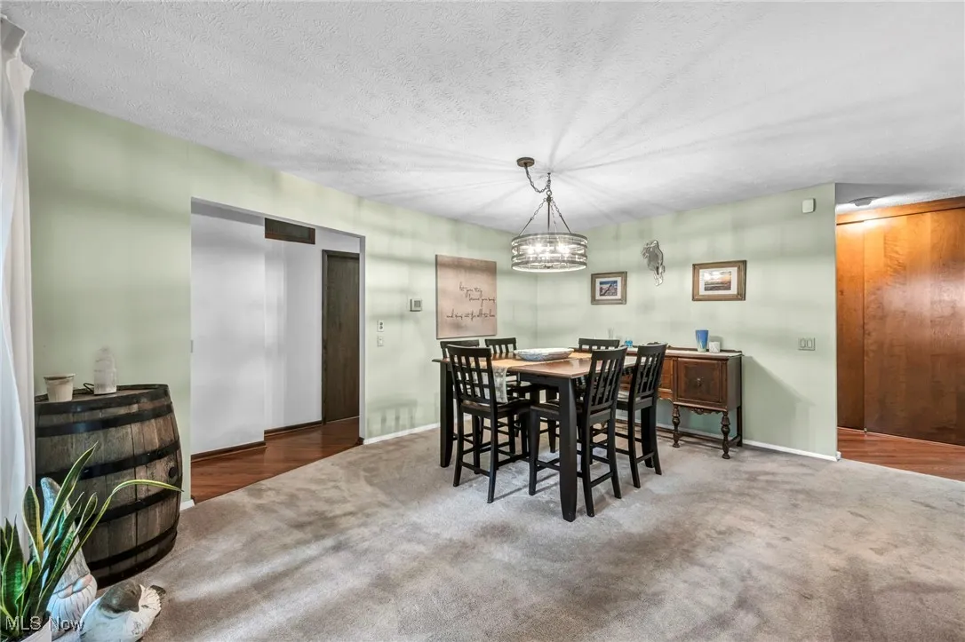 Dining area with a textured ceiling, a chandelier, carpet floors, and wood finished floors