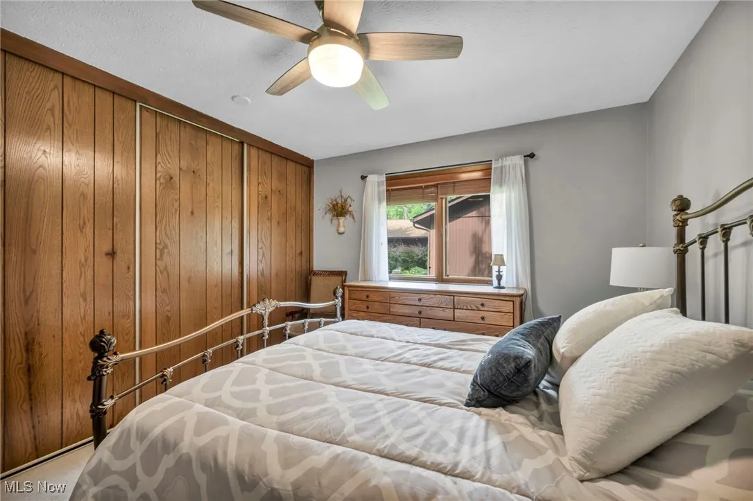 Bedroom with a closet, wooden walls, a ceiling fan, and carpet floors