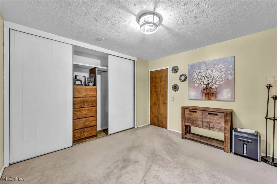 Carpeted bedroom featuring a textured ceiling and a closet