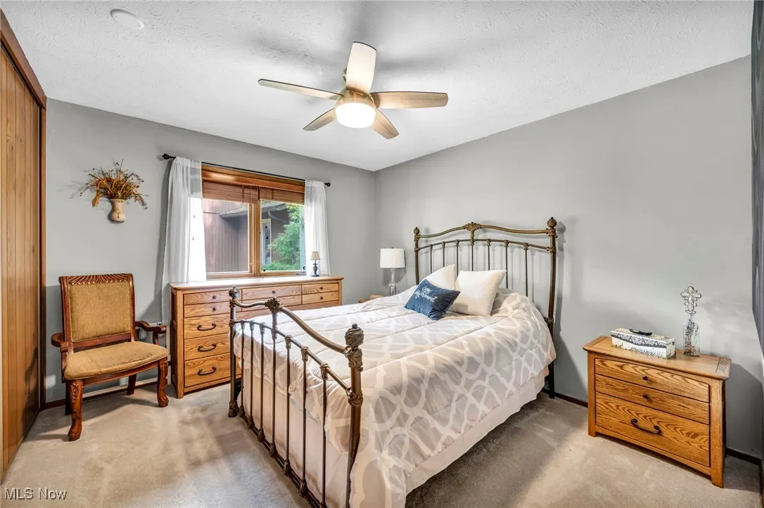 Bedroom featuring light carpet, a ceiling fan, a textured ceiling, and a closet