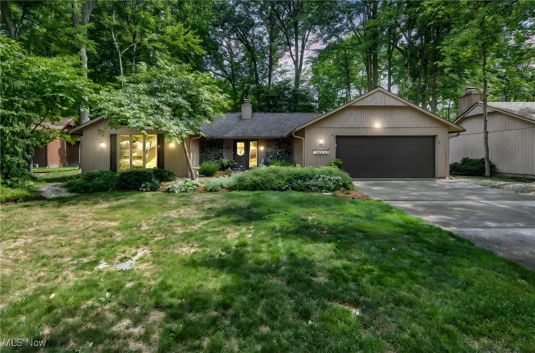 View of front of house featuring an attached garage, driveway, a chimney, and a front yard