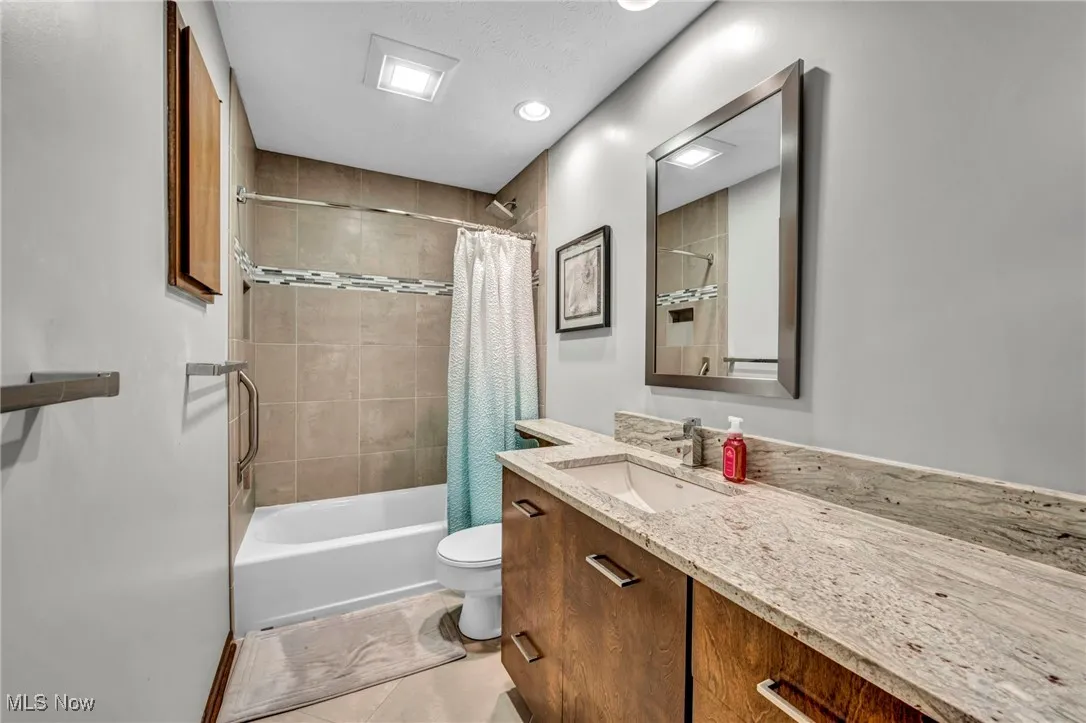 Full bathroom featuring shower / bath combo, vanity, light tile patterned floors, and recessed lighting