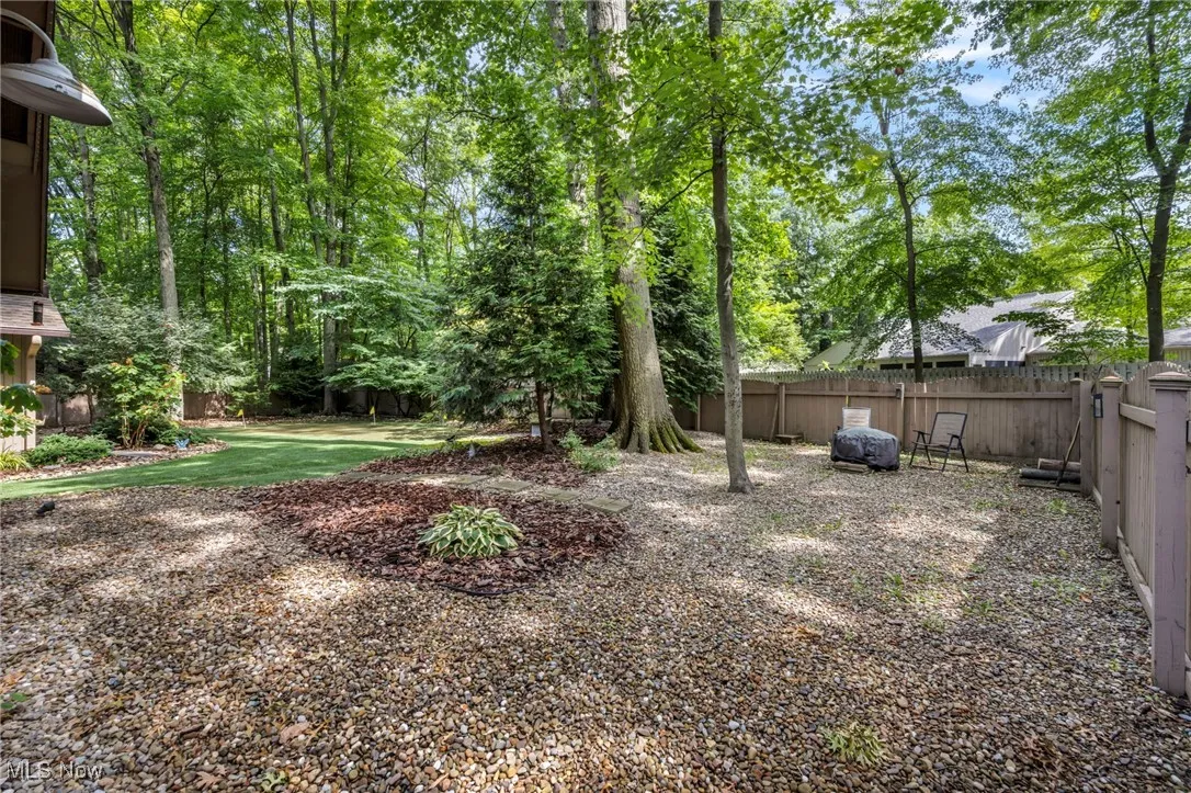 Fenced backyard with view of wooded area