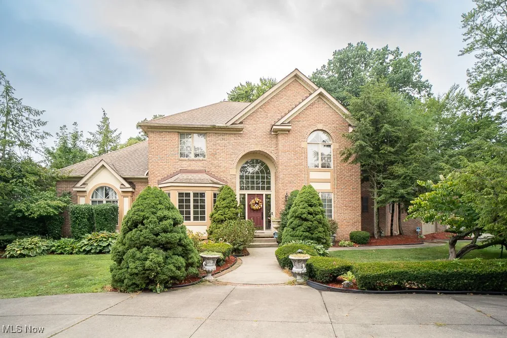 View of front facade with brick siding, a front yard, and a shingled roof